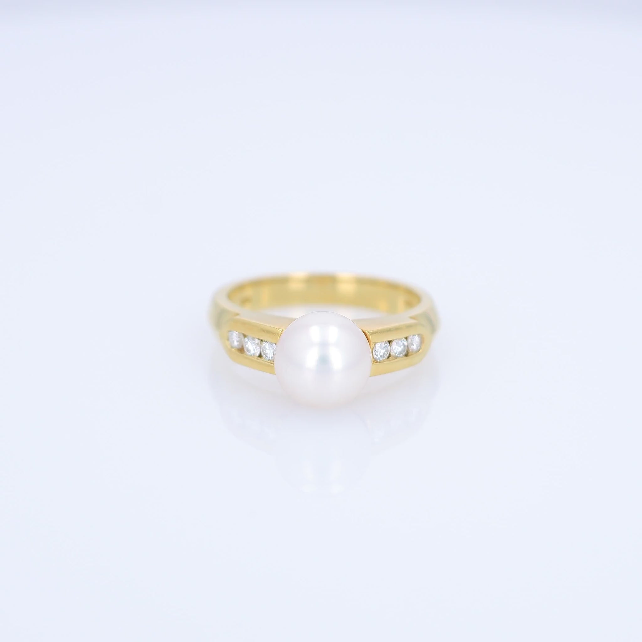 Yellow gold akoya pearl and diamond row ring on a white background