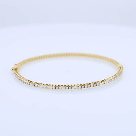 Thin yellow gold bracelet with diamonds on a white background