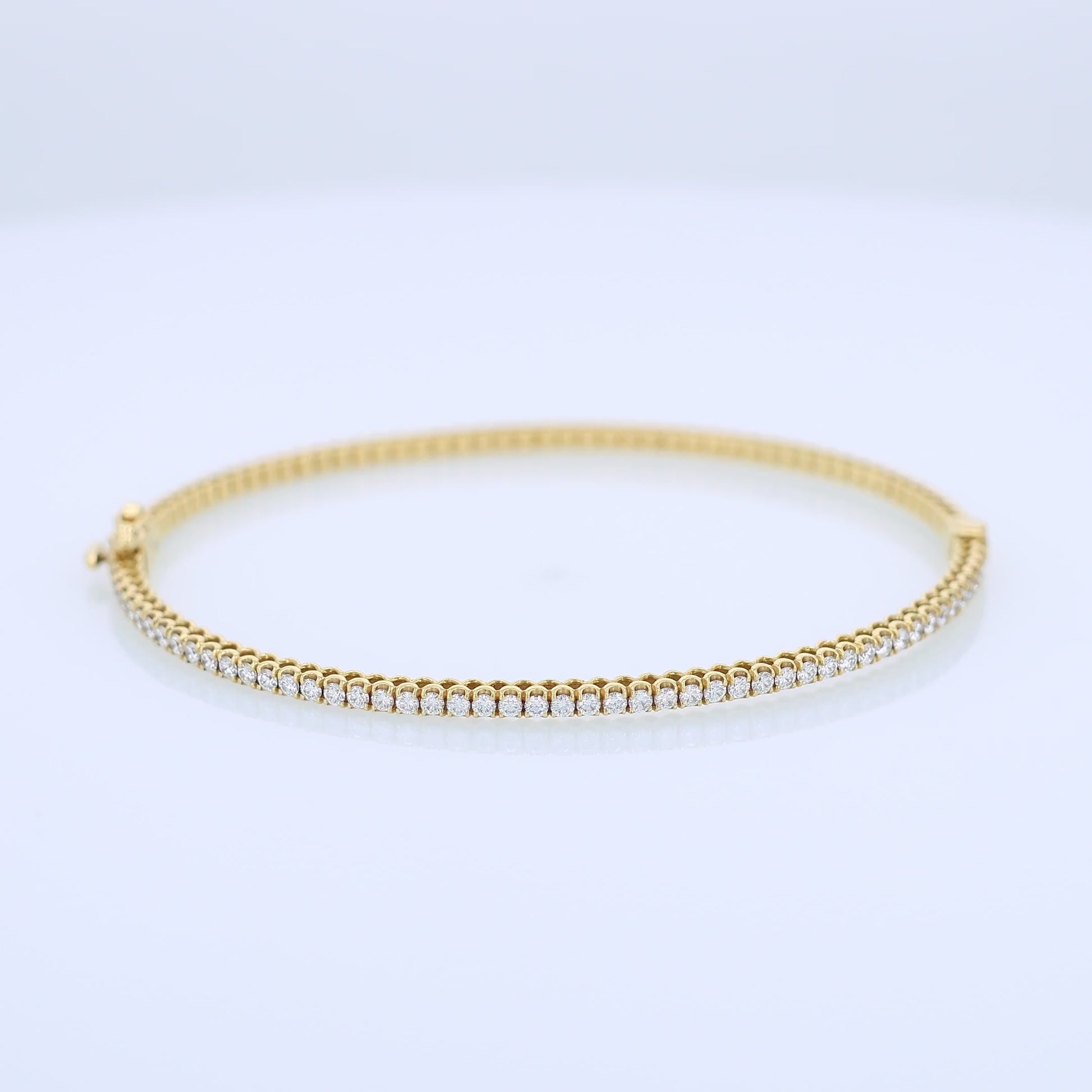 Thin yellow gold bracelet with diamonds on a white background