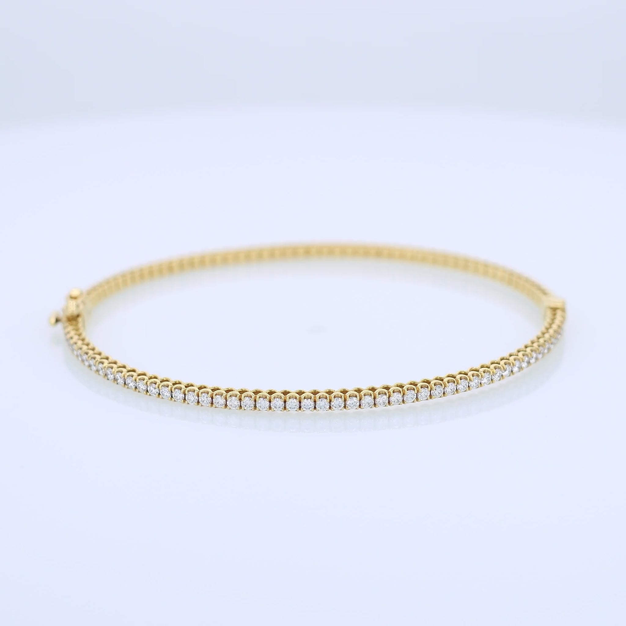 Thin yellow gold bracelet with diamonds on a white background