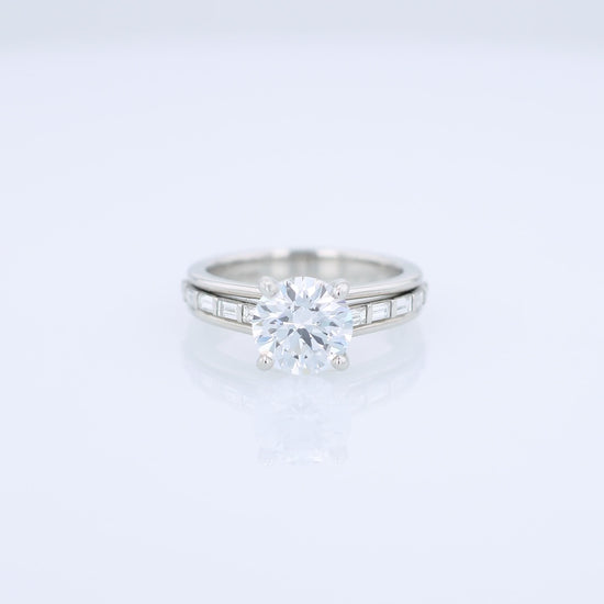 Platinum diamond engagement ring with baguette diamond accents a round cubic zirconia center on a white background