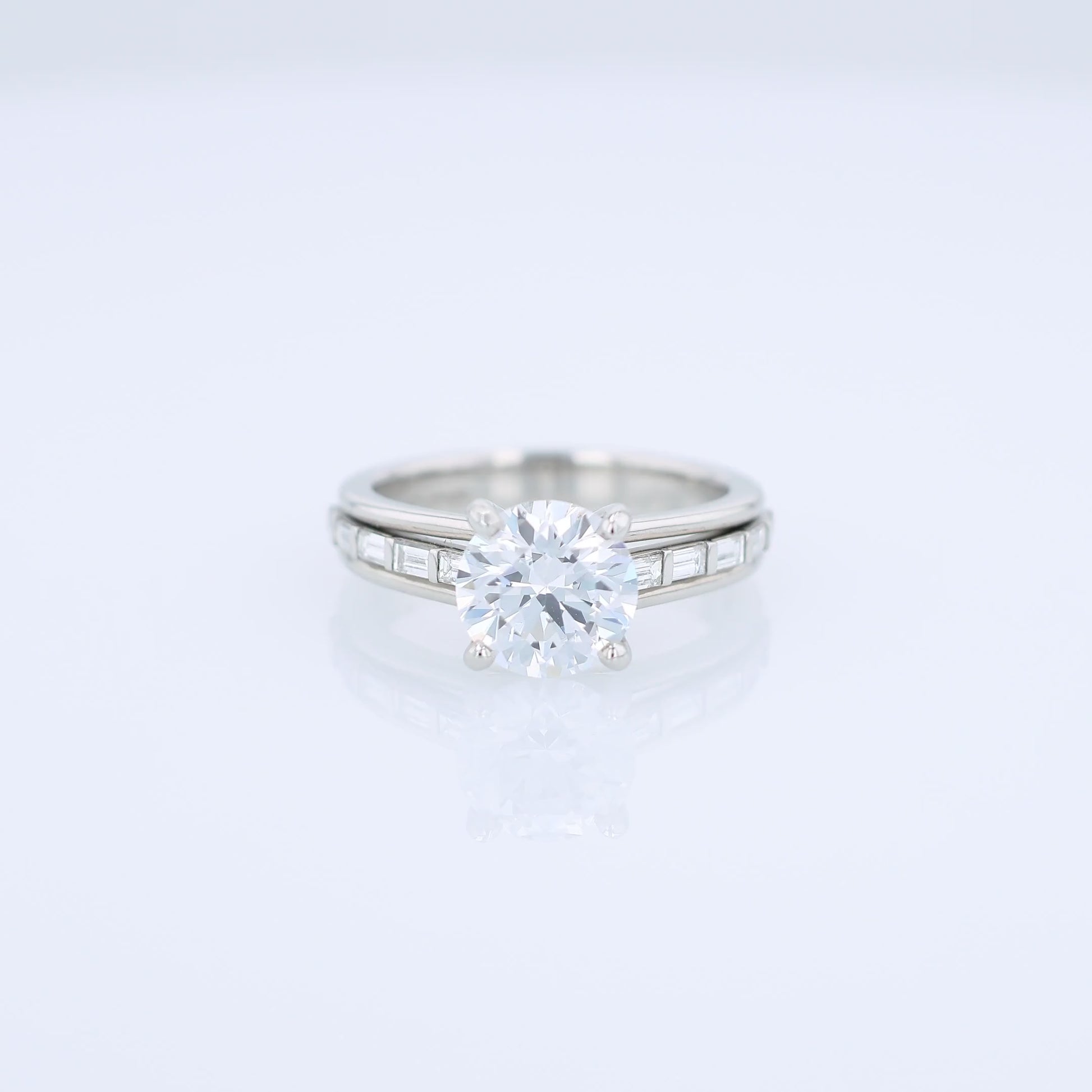 Platinum diamond engagement ring with baguette diamond accents a round cubic zirconia center on a white background