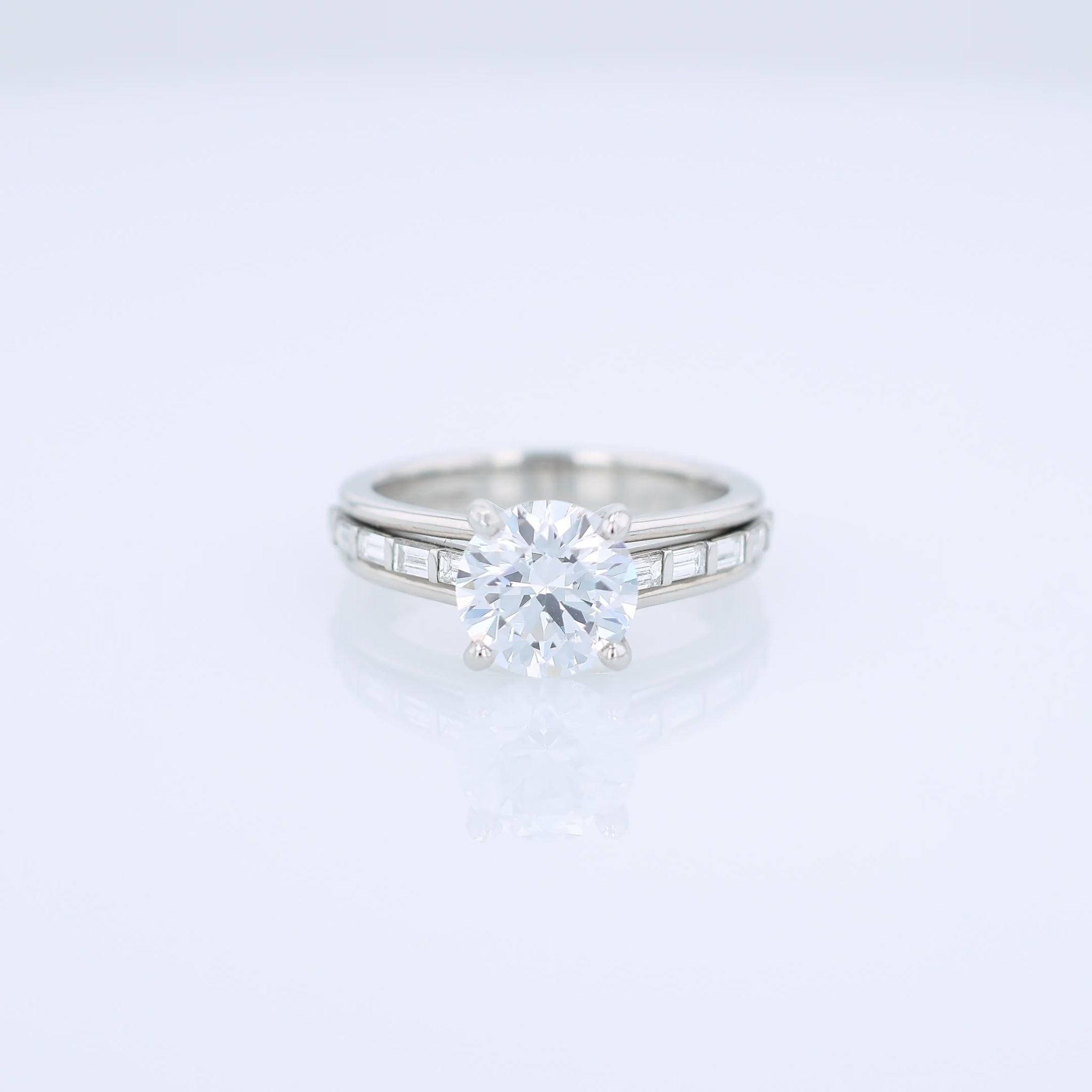 Platinum diamond engagement ring with baguette diamond accents a round cubic zirconia center on a white background