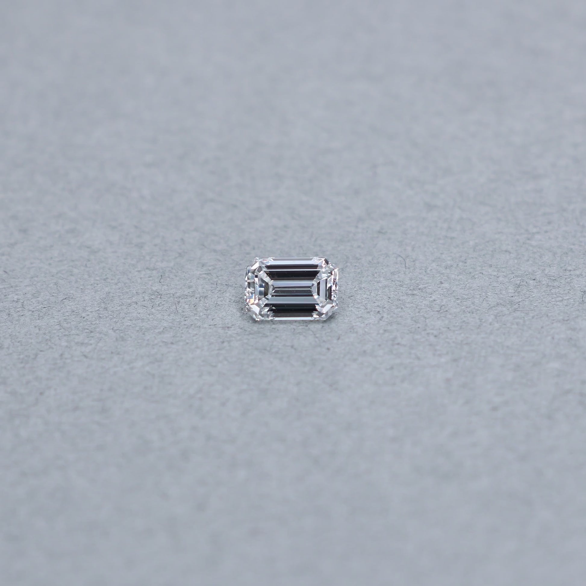Emerald cut 1.03 carat GIA certified diamond graded DVS1 on a grey background