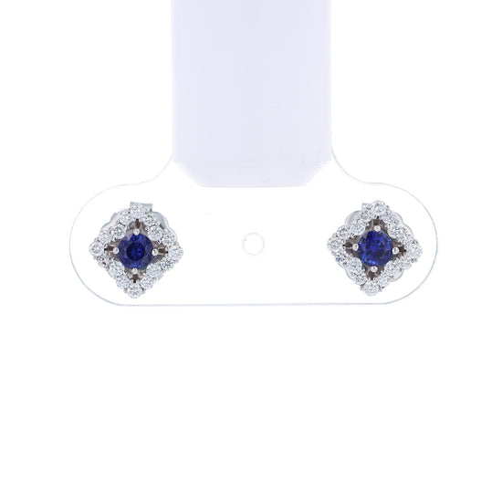 Pair of earrings with round blue sapphire centers and surrounding diamond halos on a white background