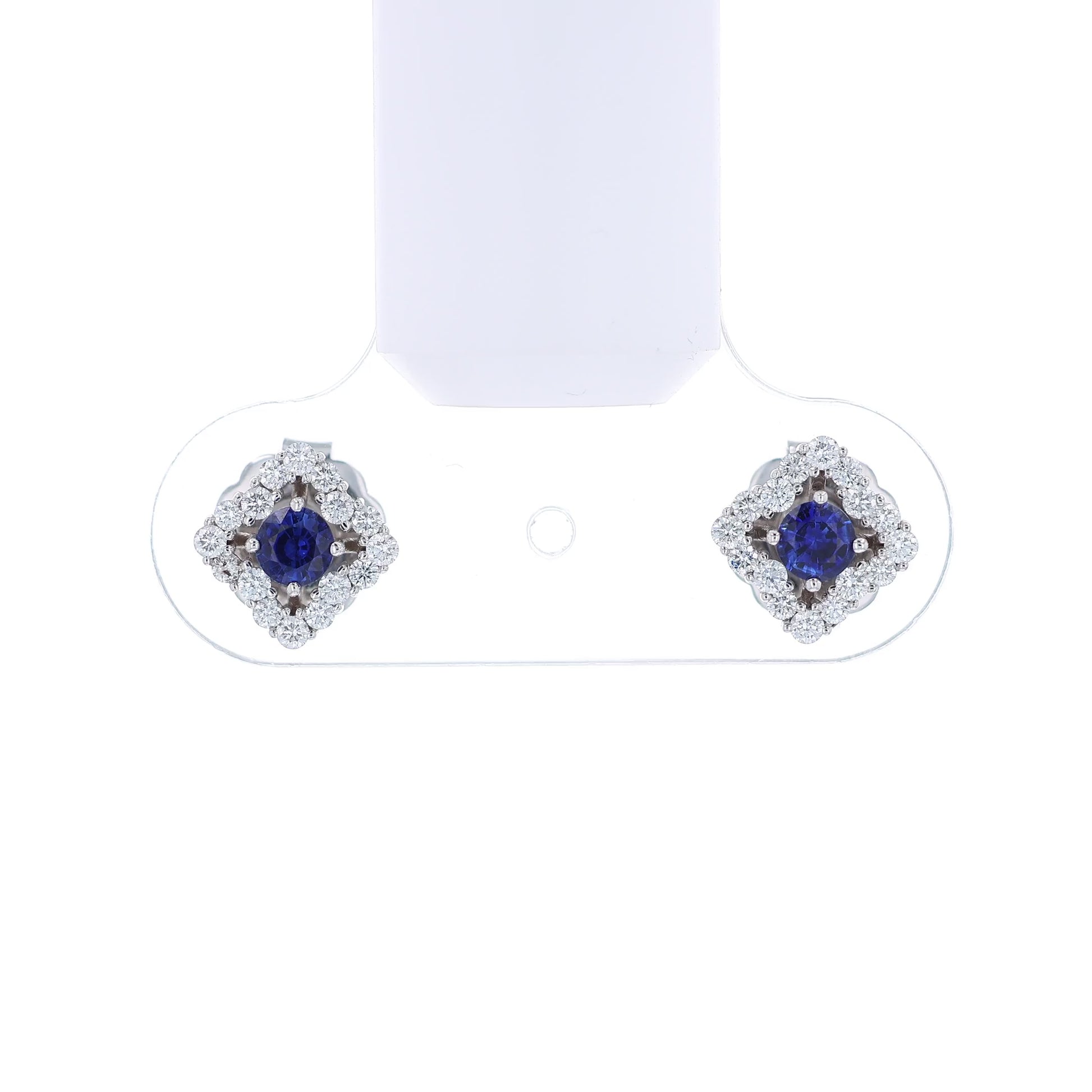 Pair of earrings with round blue sapphire centers and surrounding diamond halos on a white background