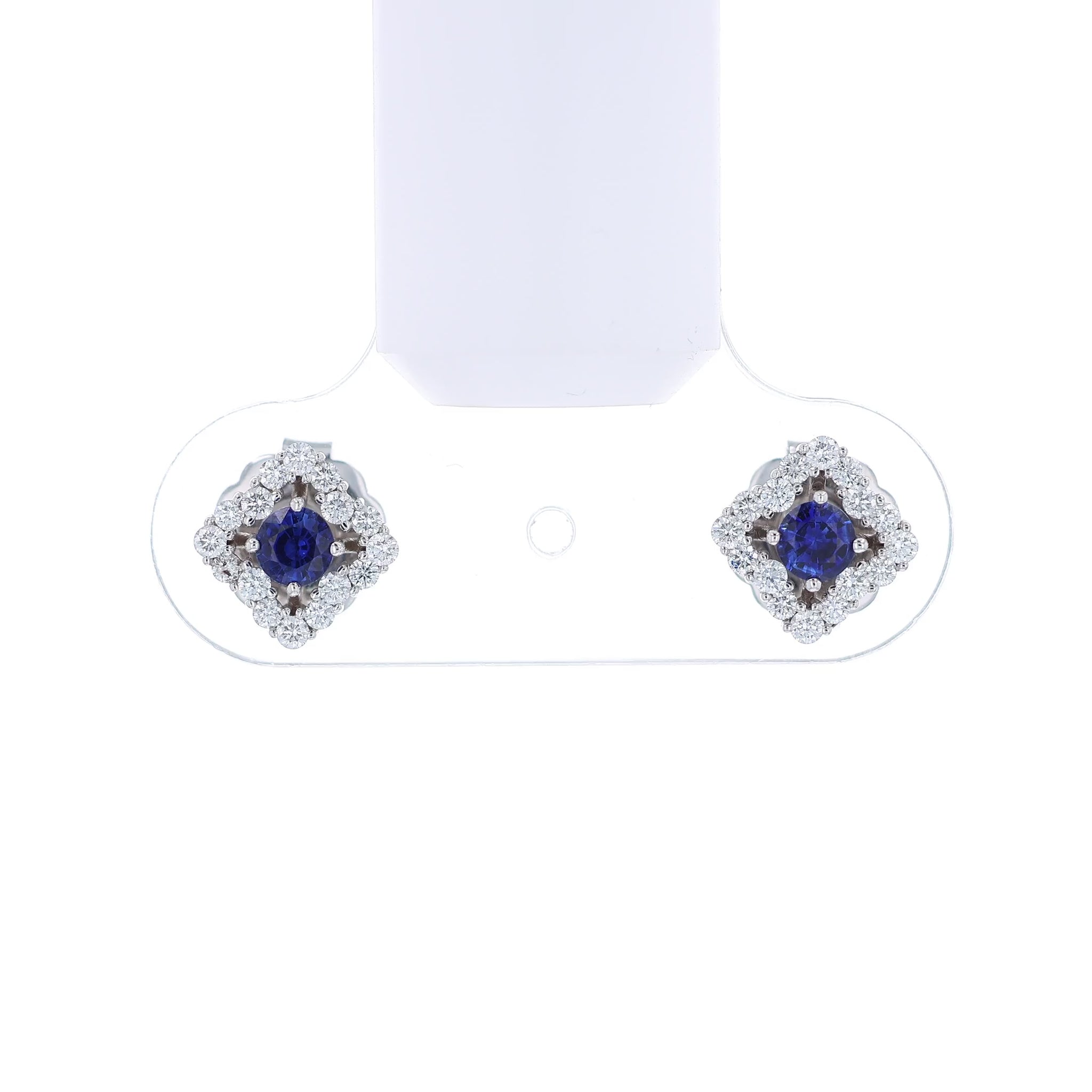 Pair of earrings with round blue sapphire centers and surrounding diamond halos on a white background