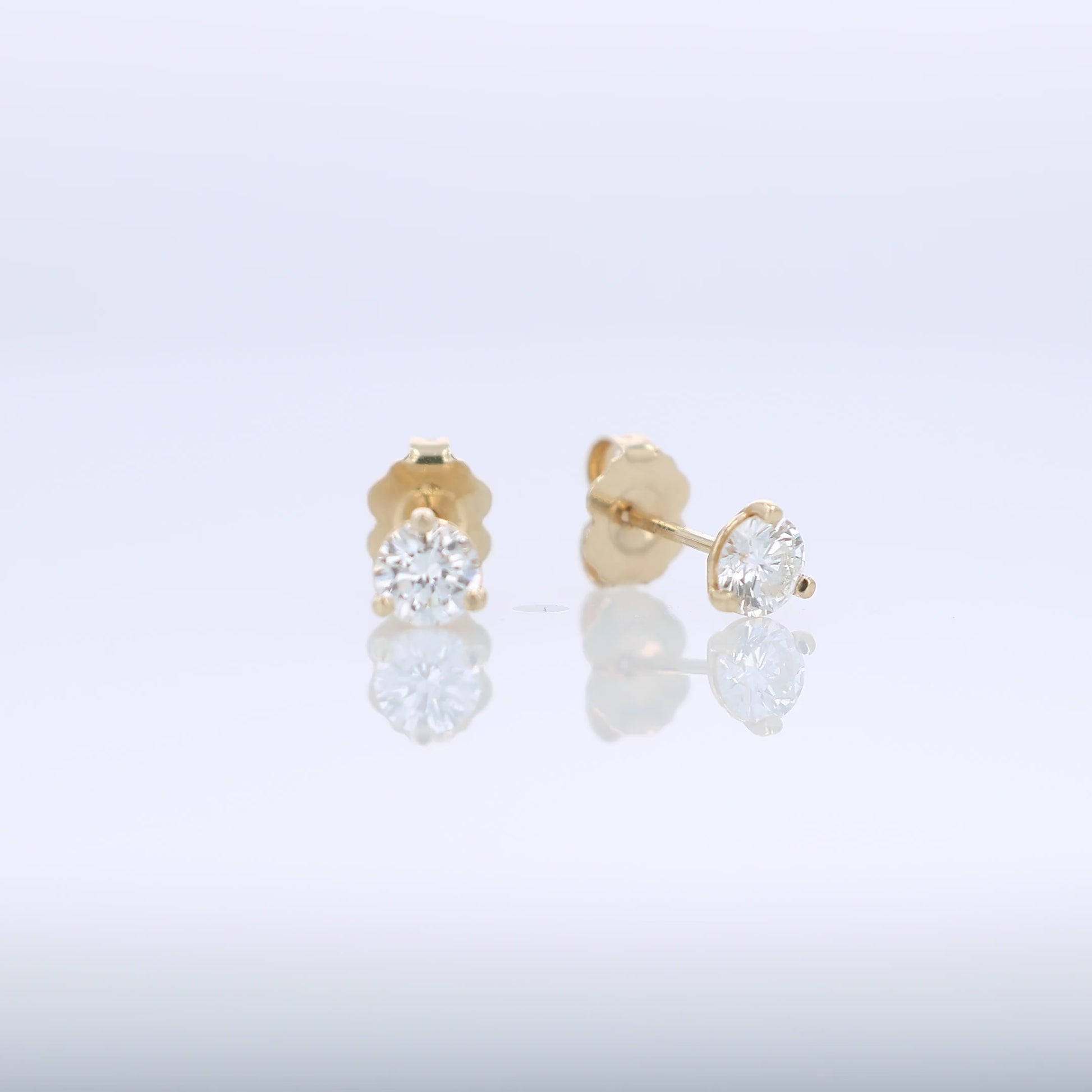 Yellow gold round brilliant cut diamond studs totaling 0.57 carats on a white background