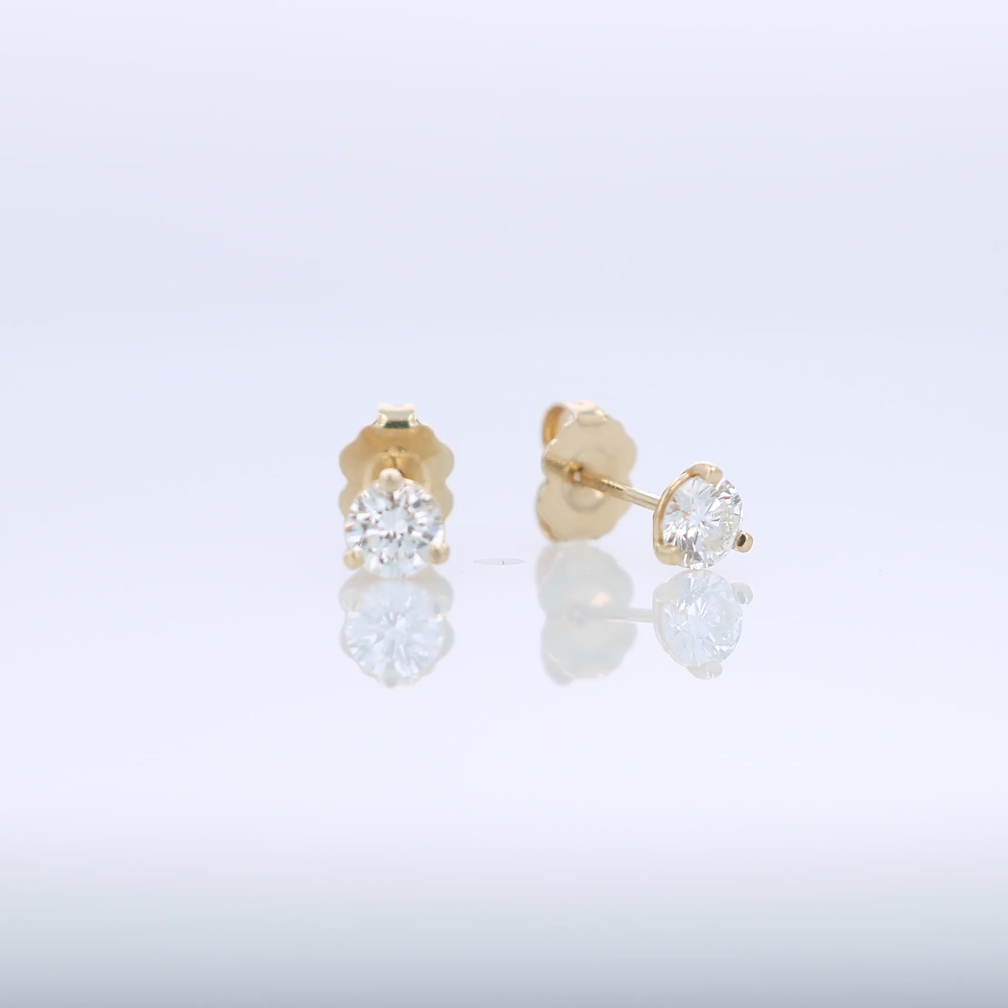 Yellow gold round brilliant cut diamond studs totaling 0.57 carats on a white background