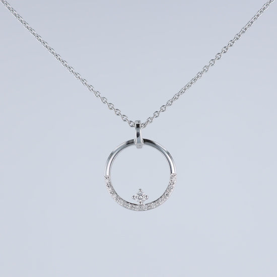 A video of a white gold chain necklace with a circular pendant featuring a small crown motif and clear stones, shown at various angles on a white background with a faint reflection below.