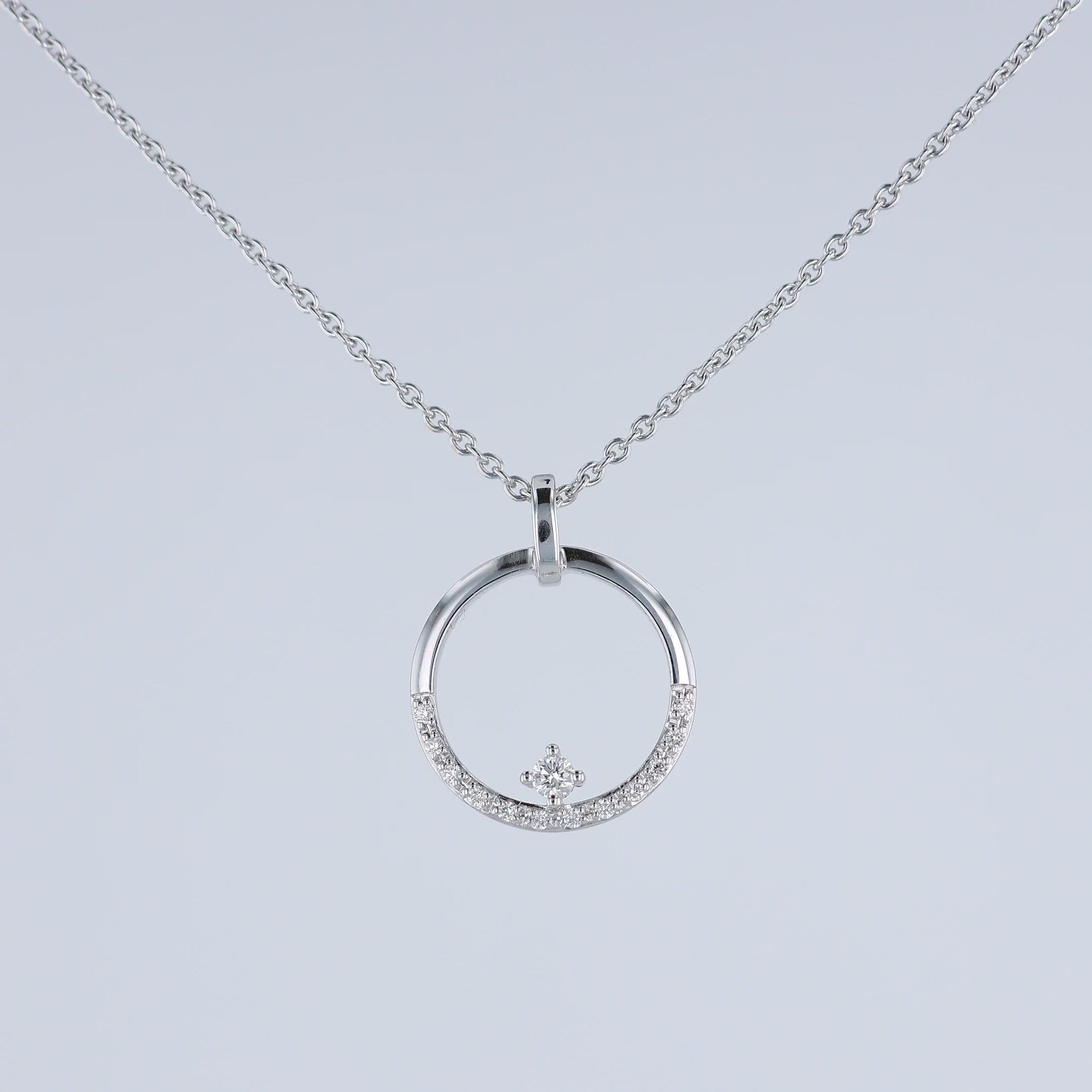 A video of a white gold chain necklace with a circular pendant featuring a small crown motif and clear stones, shown at various angles on a white background with a faint reflection below.