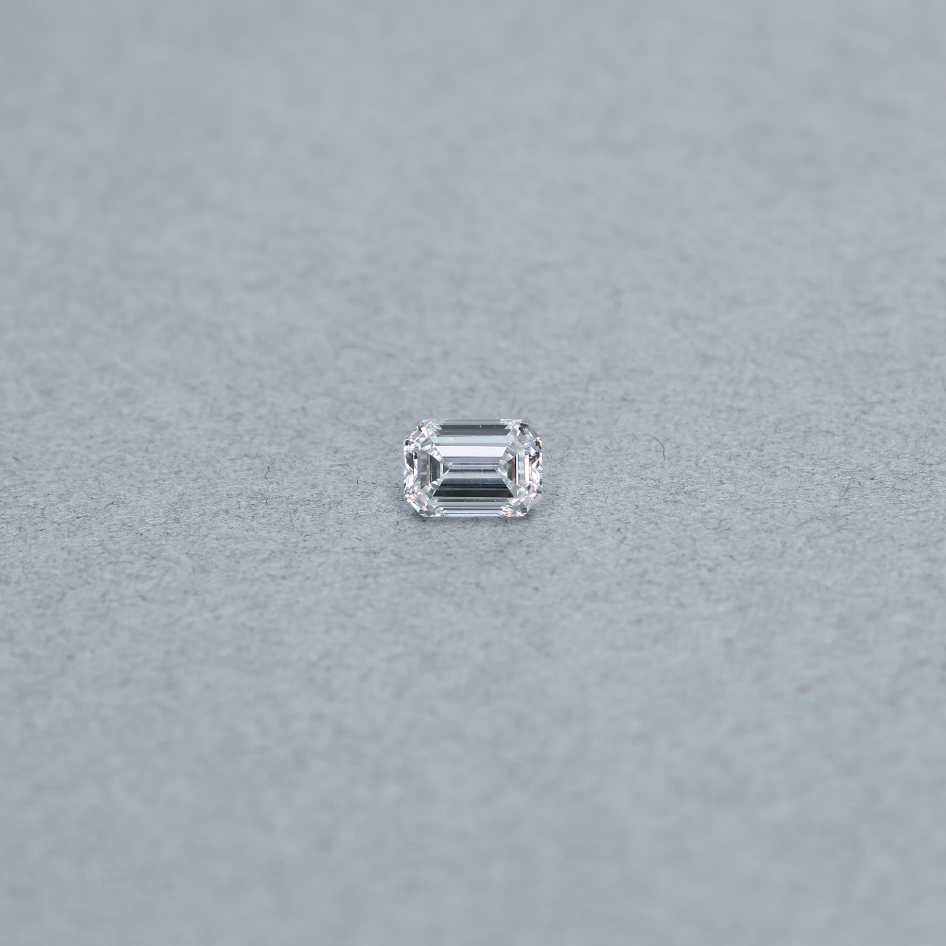 Emerald Cut .90 carat GIA certified diamond graded GVS1 on a grey background