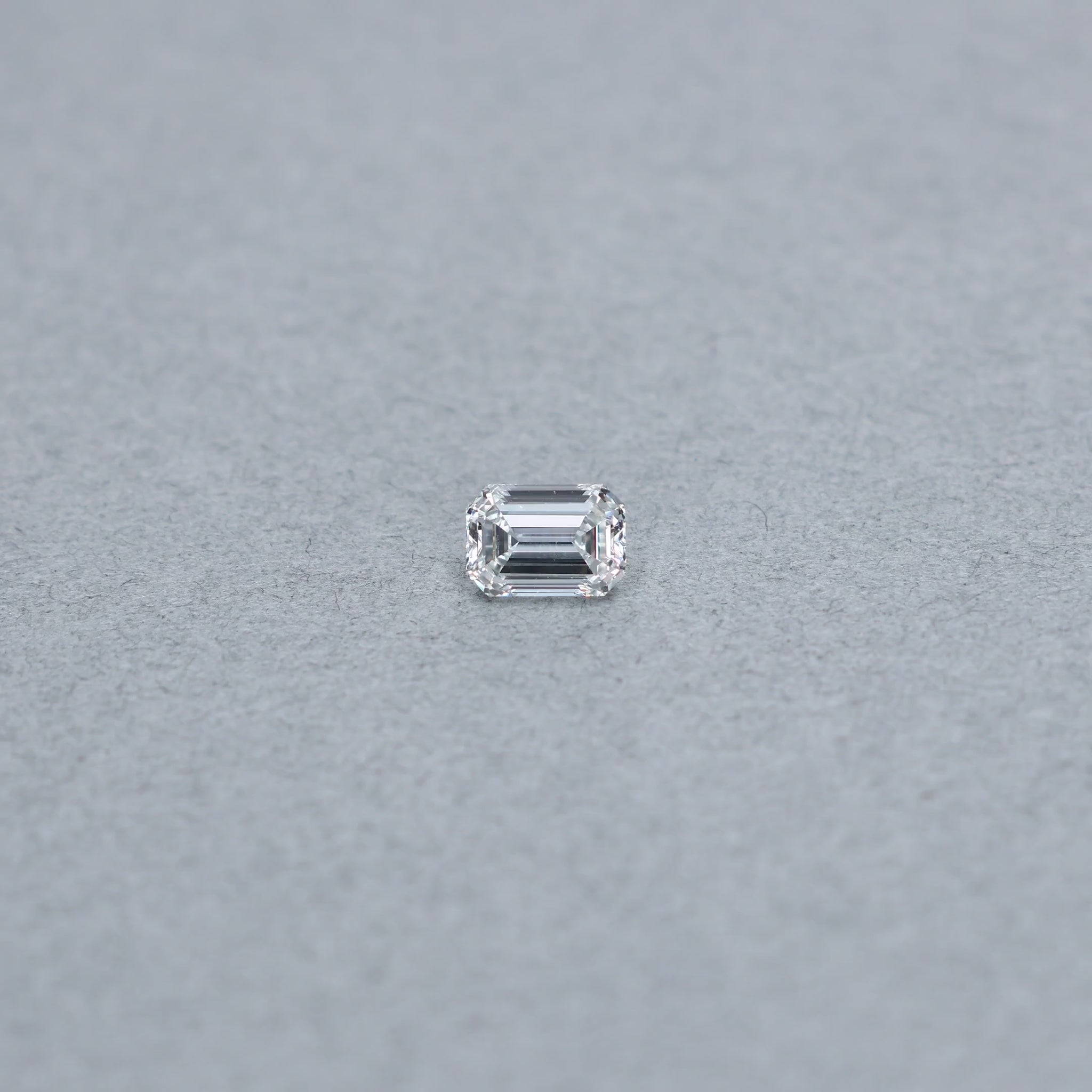 Emerald Cut .90 carat GIA certified diamond graded GVS1 on a grey background