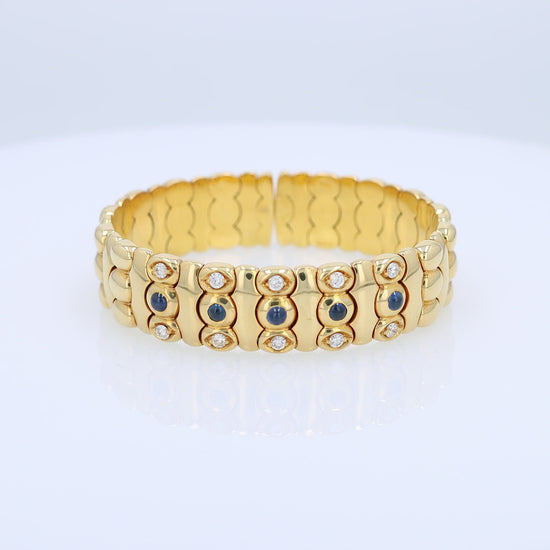 Yellow gold diamond and cabochon sapphire flexible cuff bracelet on a white background