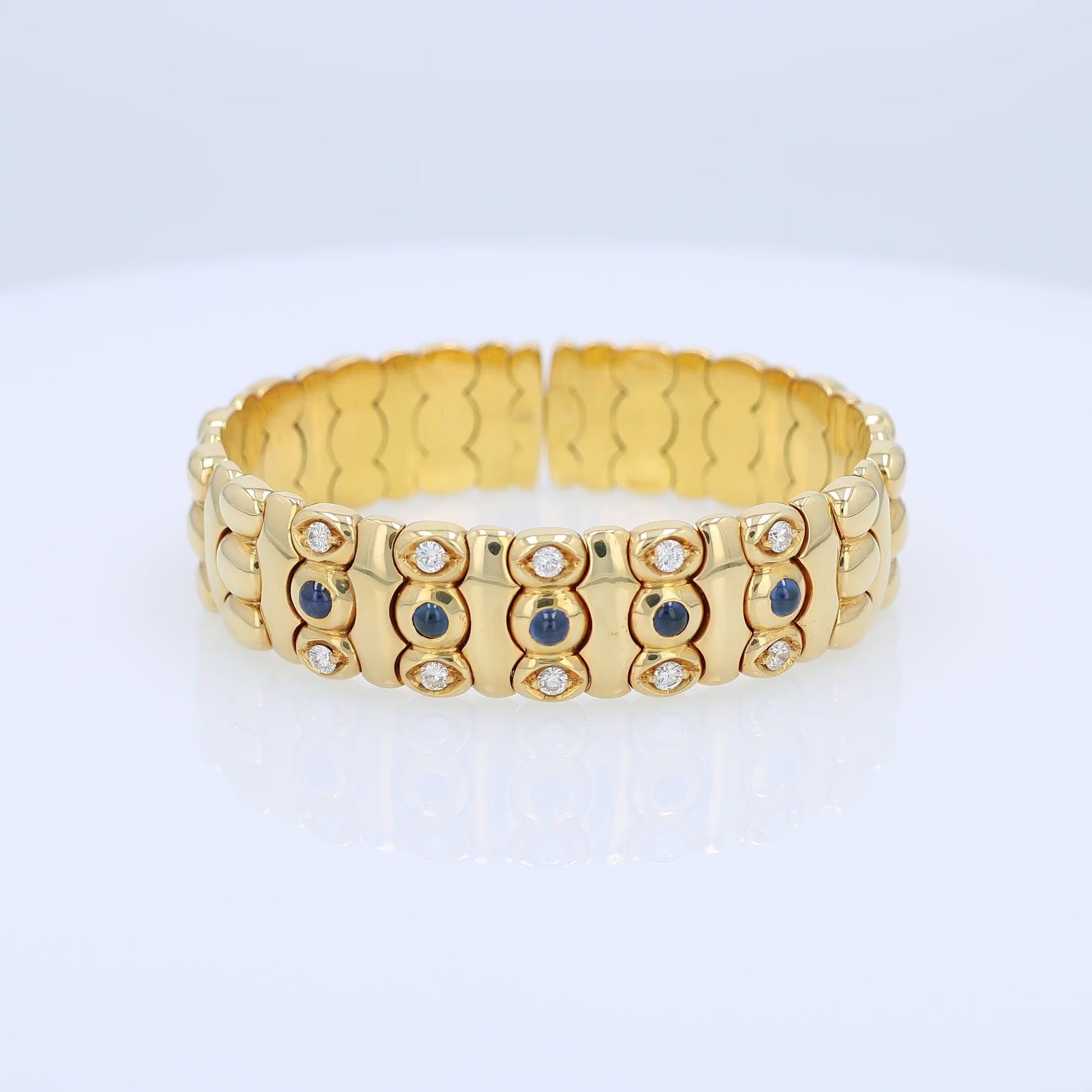 Yellow gold diamond and cabochon sapphire flexible cuff bracelet on a white background