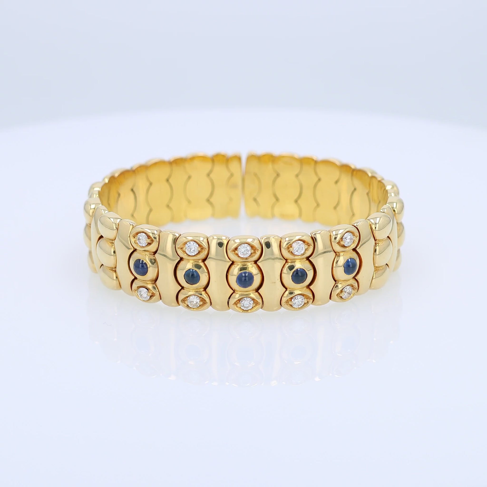 Yellow gold diamond and cabochon sapphire flexible cuff bracelet on a white background