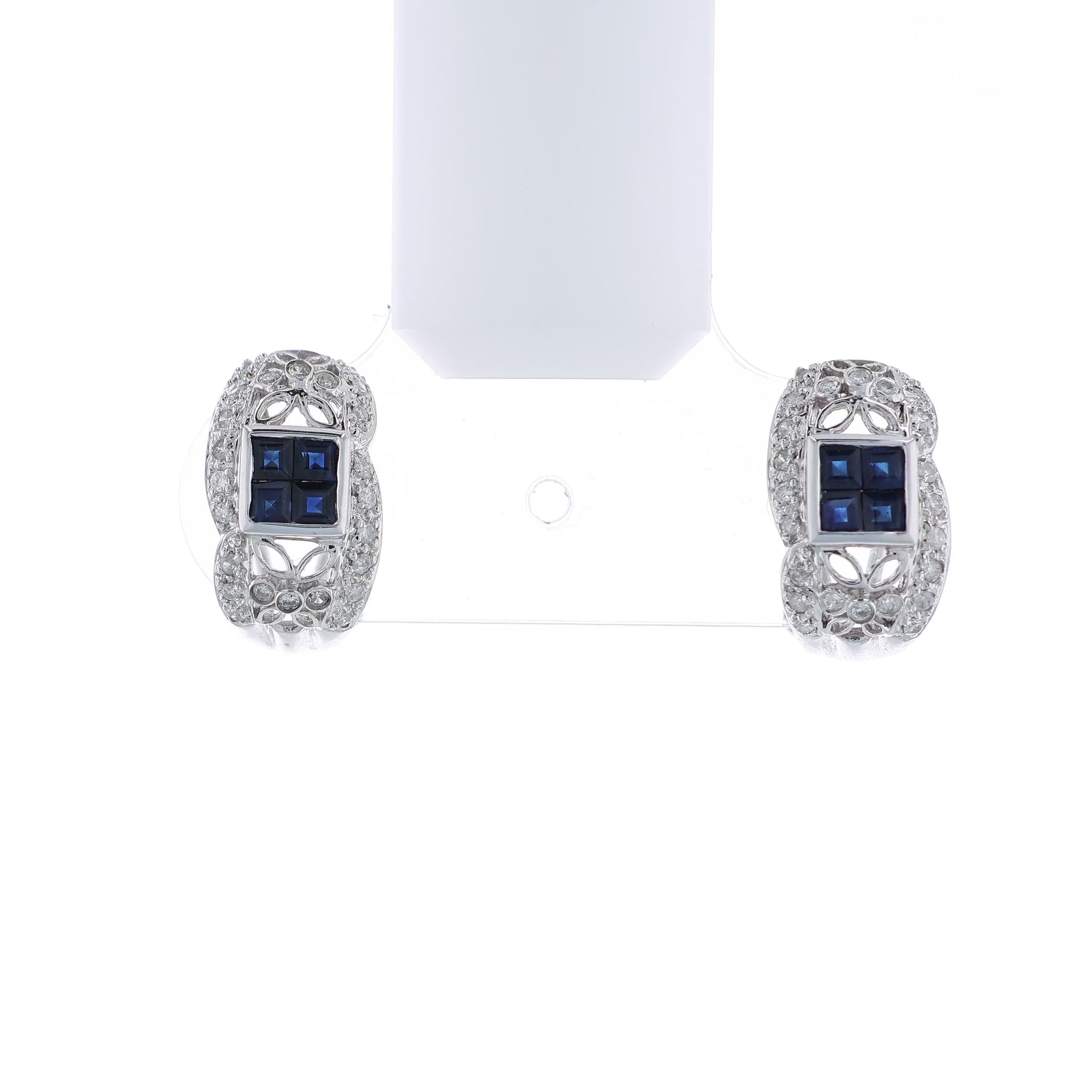 Pair of white gold diamond hoop earrings with multi-square blue sapphire centers on a white background