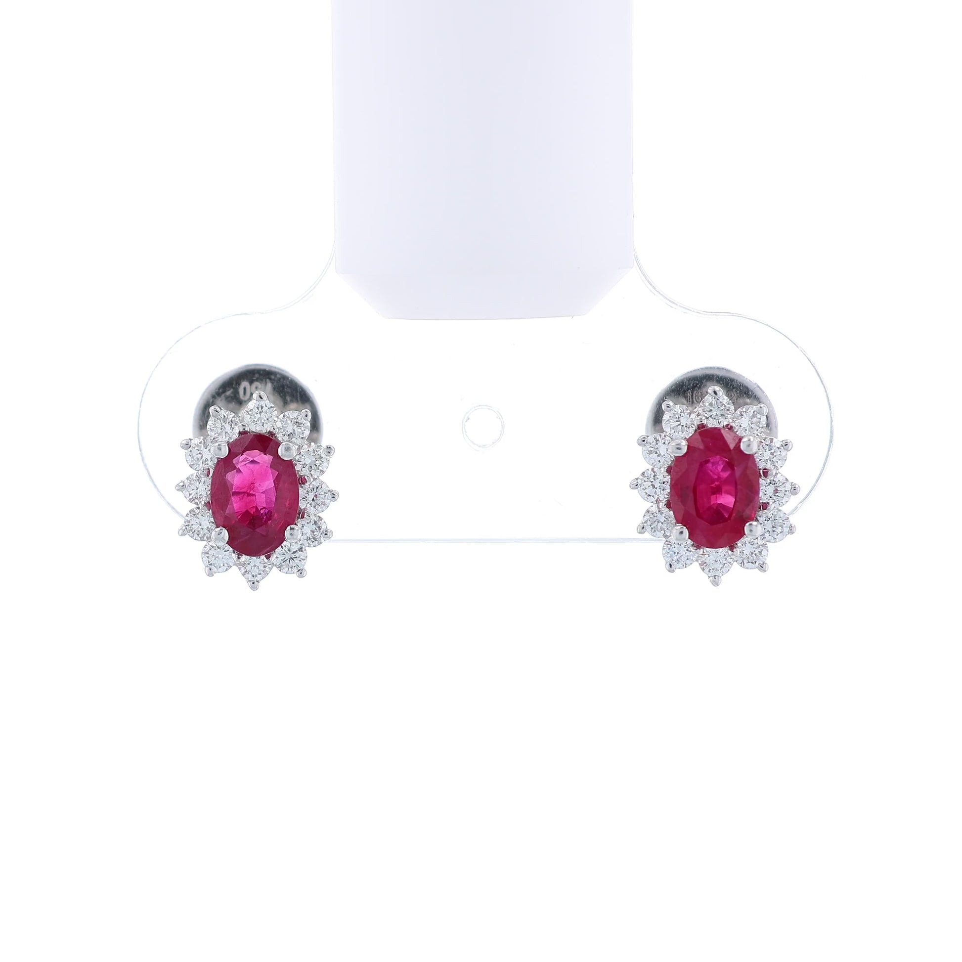 Pair of white gold diamond halo earrings with oval ruby centers on a white background