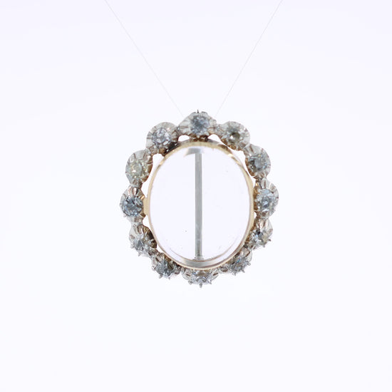 Two-tone gold pin with a clear locket center and surrounding diamonds on a white background