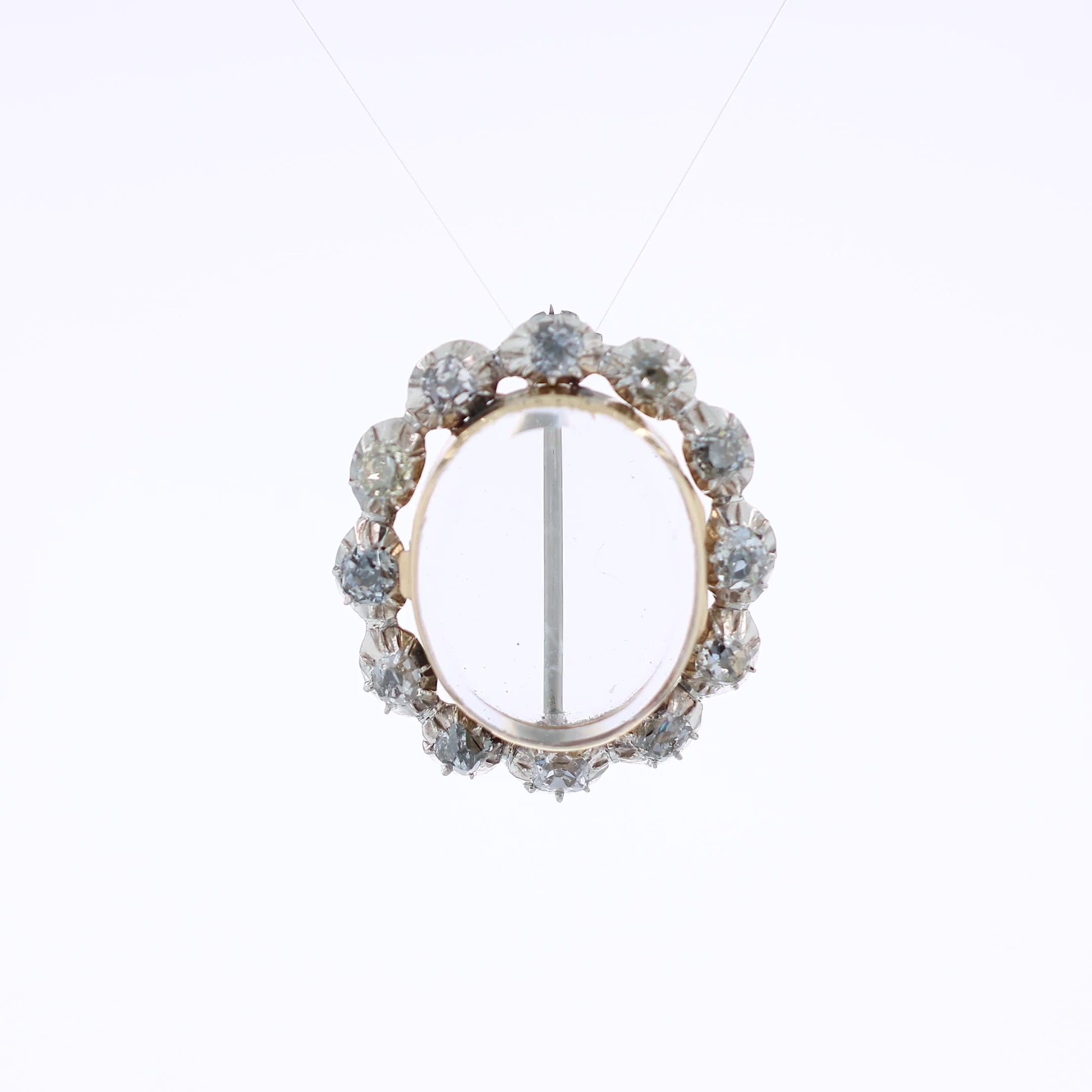 Two-tone gold pin with a clear locket center and surrounding diamonds on a white background