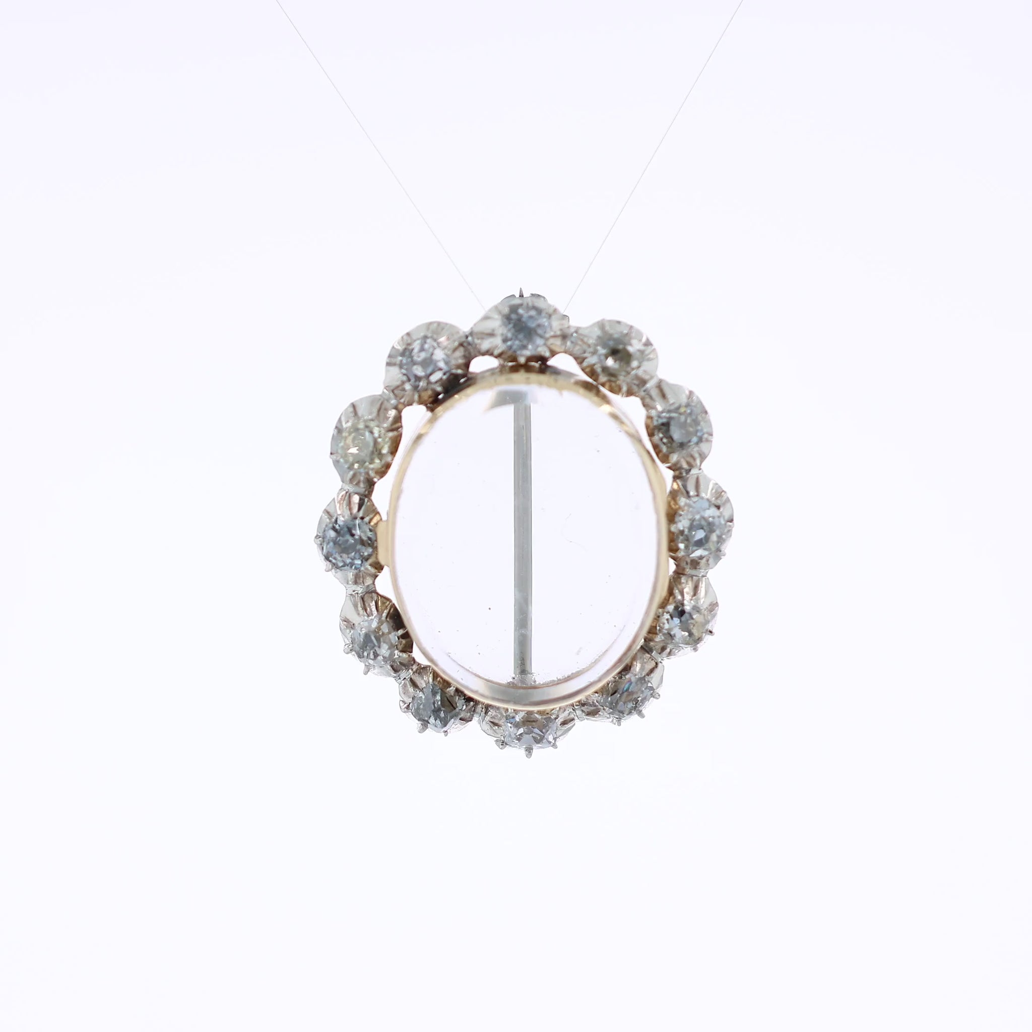 Two-tone gold pin with a clear locket center and surrounding diamonds on a white background