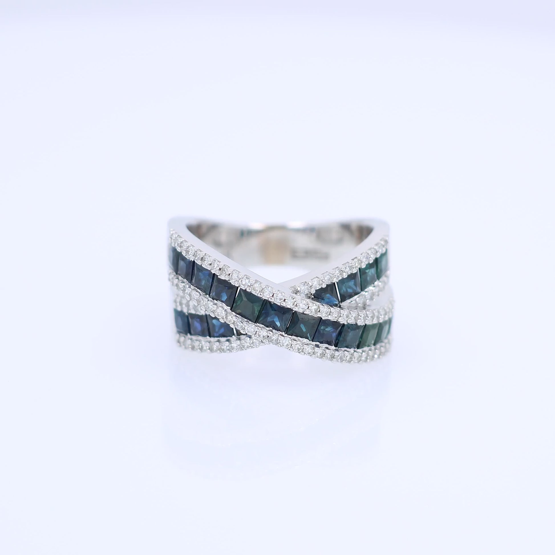 White gold crisscross design channel-set sapphire and diamond ring on a white background