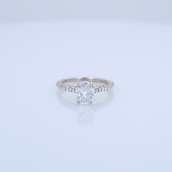 Two-tone gold diamond engagement ring with diamond accents and an oval cubic zirconia center on a white background