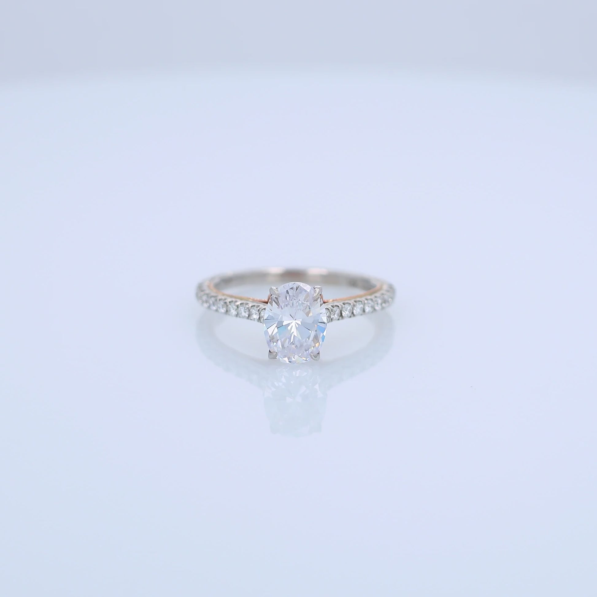 Two-tone gold diamond engagement ring with diamond accents and an oval cubic zirconia center on a white background