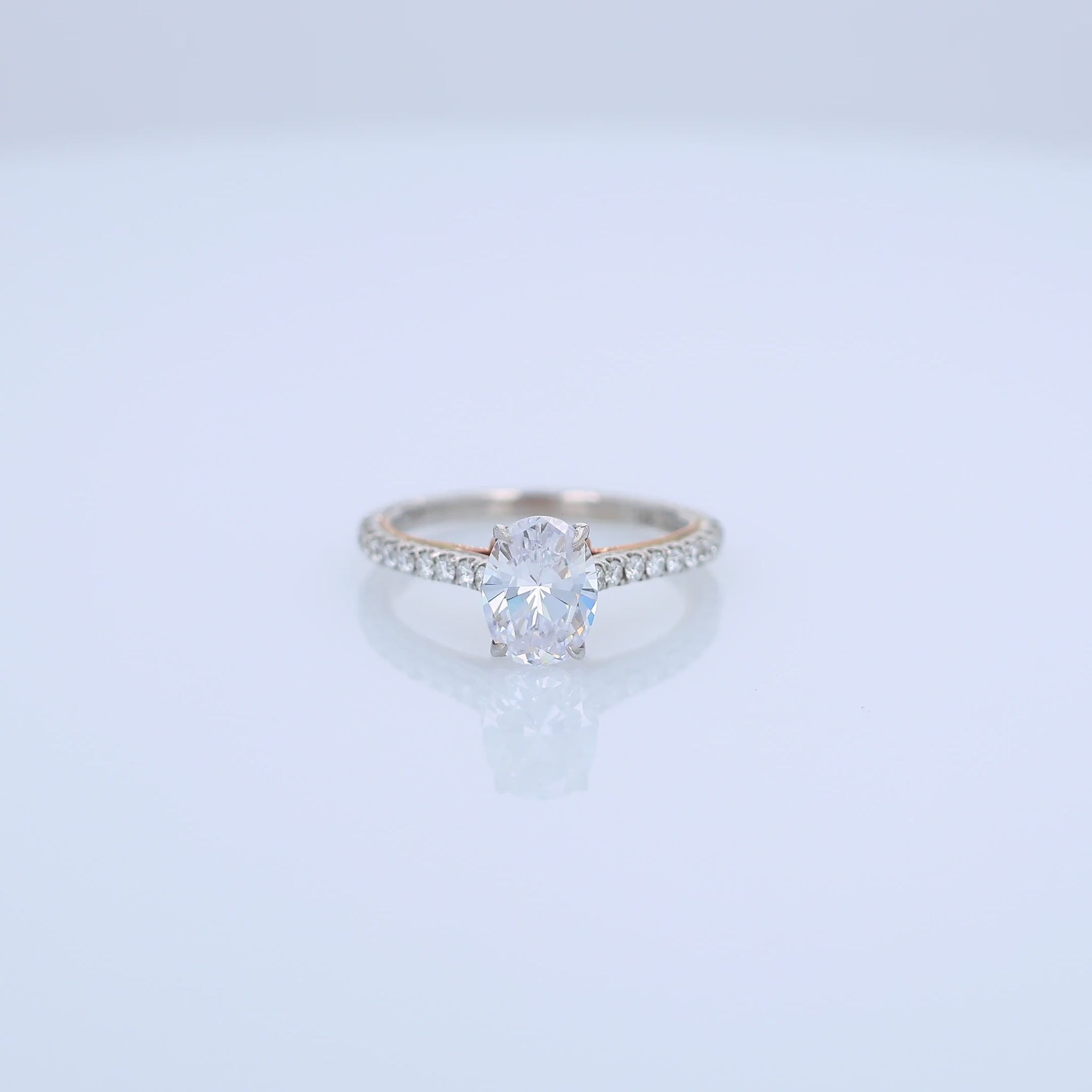 Two-tone gold diamond engagement ring with diamond accents and an oval cubic zirconia center on a white background