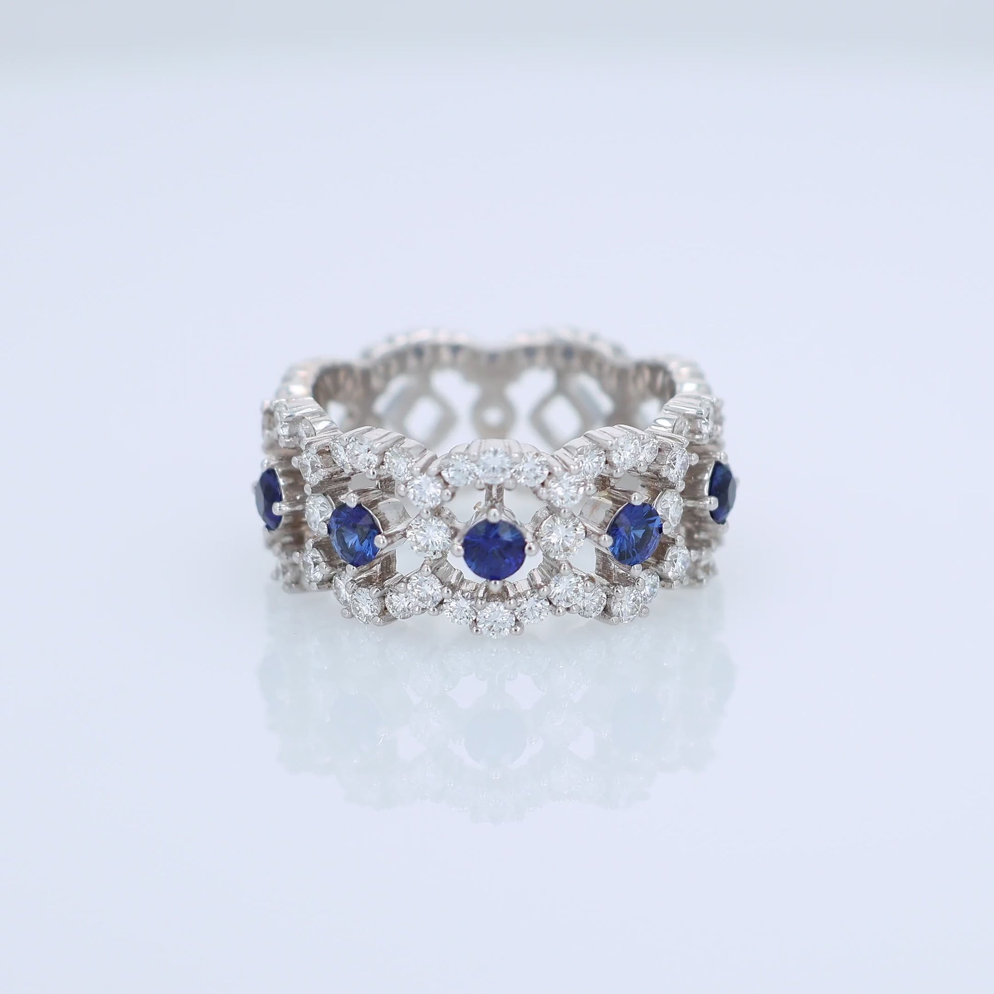 White gold open work band with diamond and blue sapphire accents on a white background