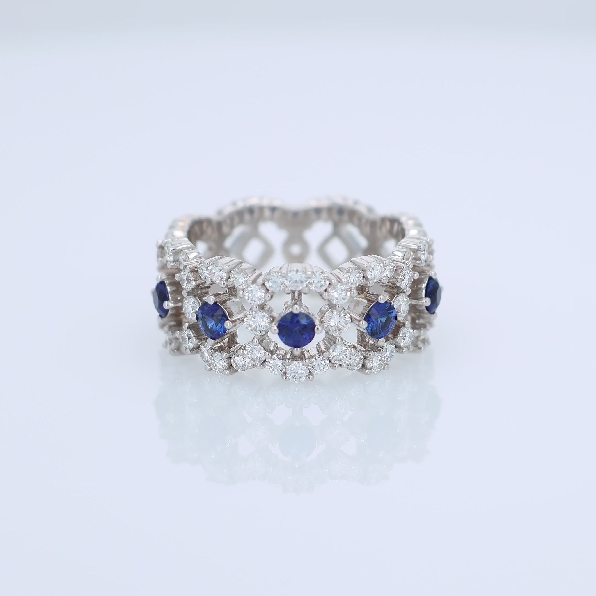 White gold open work band with diamond and blue sapphire accents on a white background