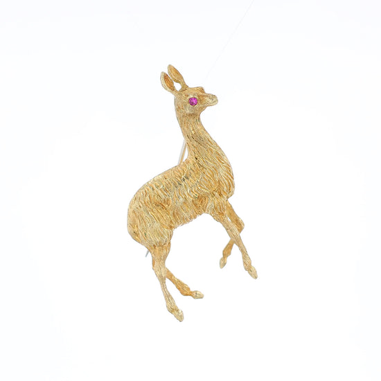 Yellow gold brushed llama pin with a pink sapphire eye on a white background
