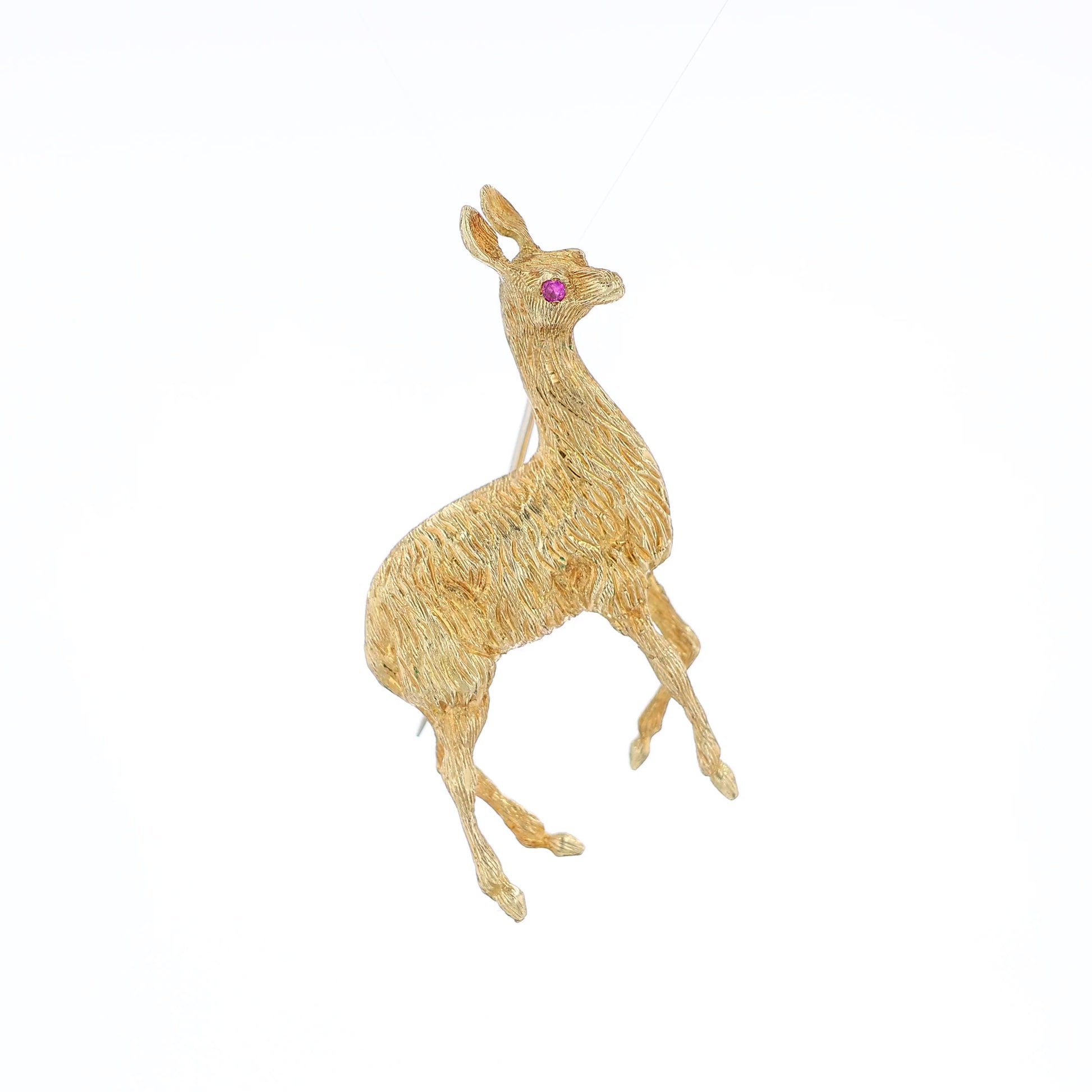 Yellow gold brushed llama pin with a pink sapphire eye on a white background