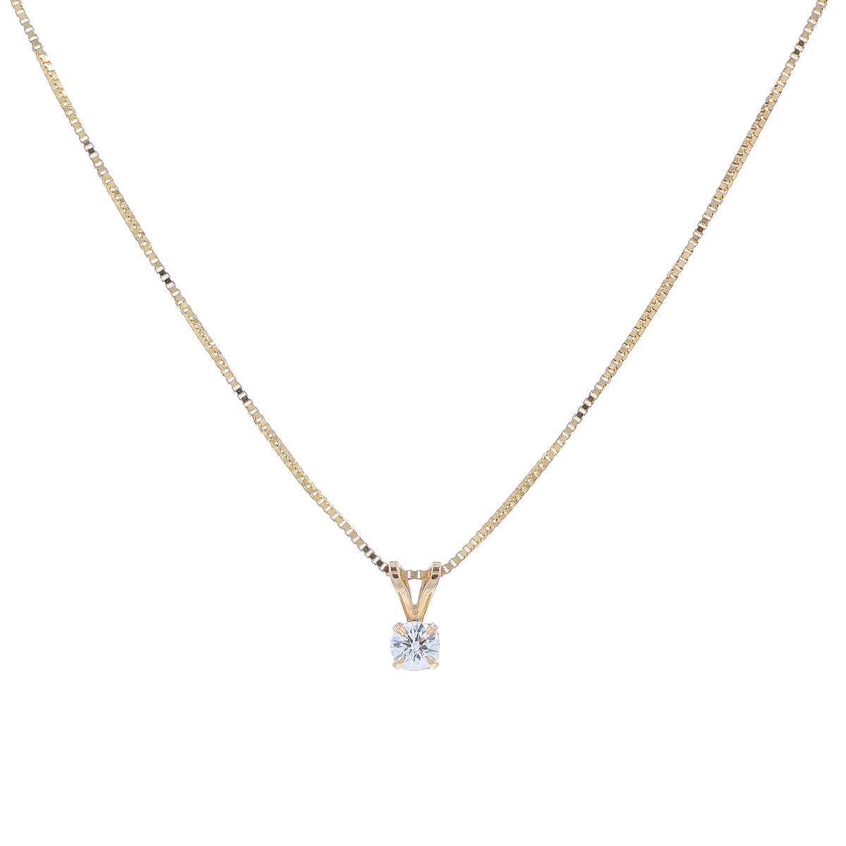 A delicate gold chain necklace with a small pendant holding a clear round-cut diamond, displayed against a solid white background.