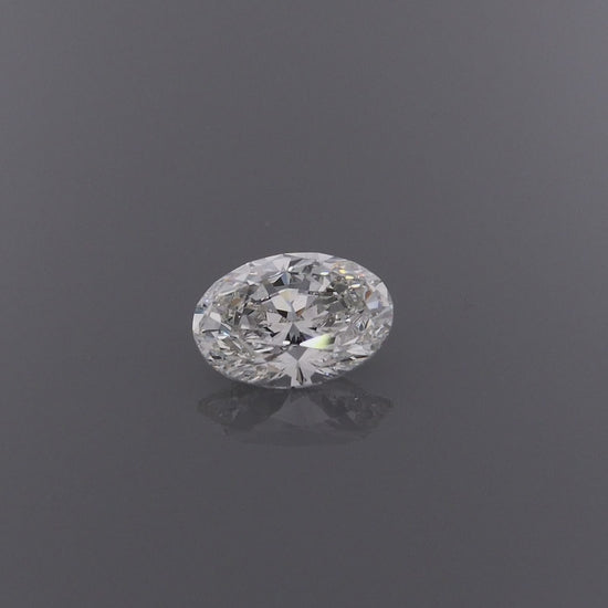 A video of an oval-cut diamond gemstone with a brilliant faceted cut, on a clean grey background with a subtle reflection below.