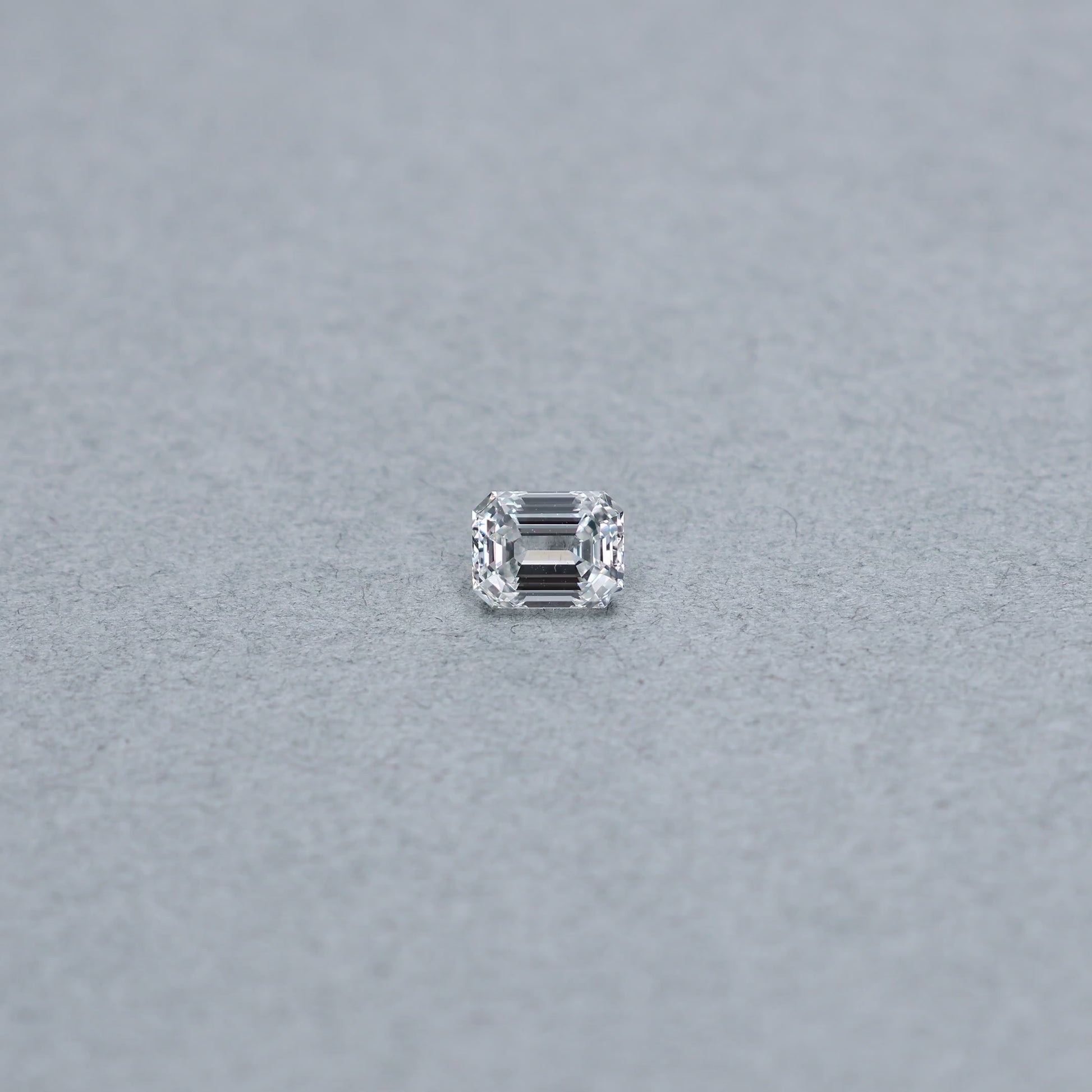 Emerald cut 1.01 carat GIA certified diamond graded FVS1 on a grey background