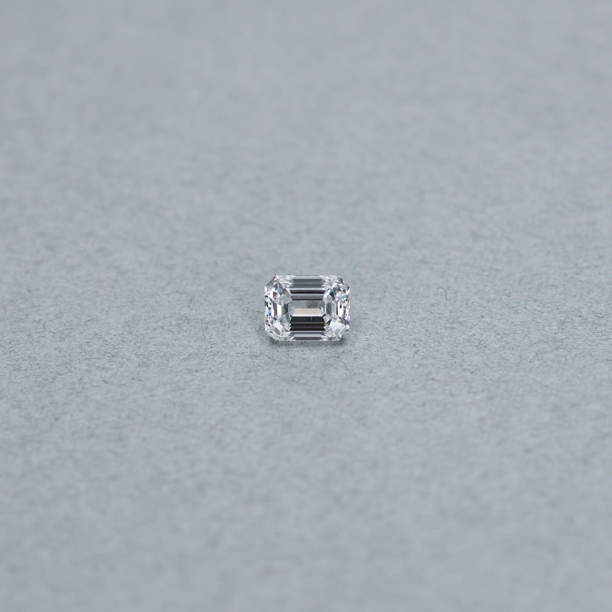 Emerald cut 1.01 carat GIA certified diamond graded FVS1 on a grey background
