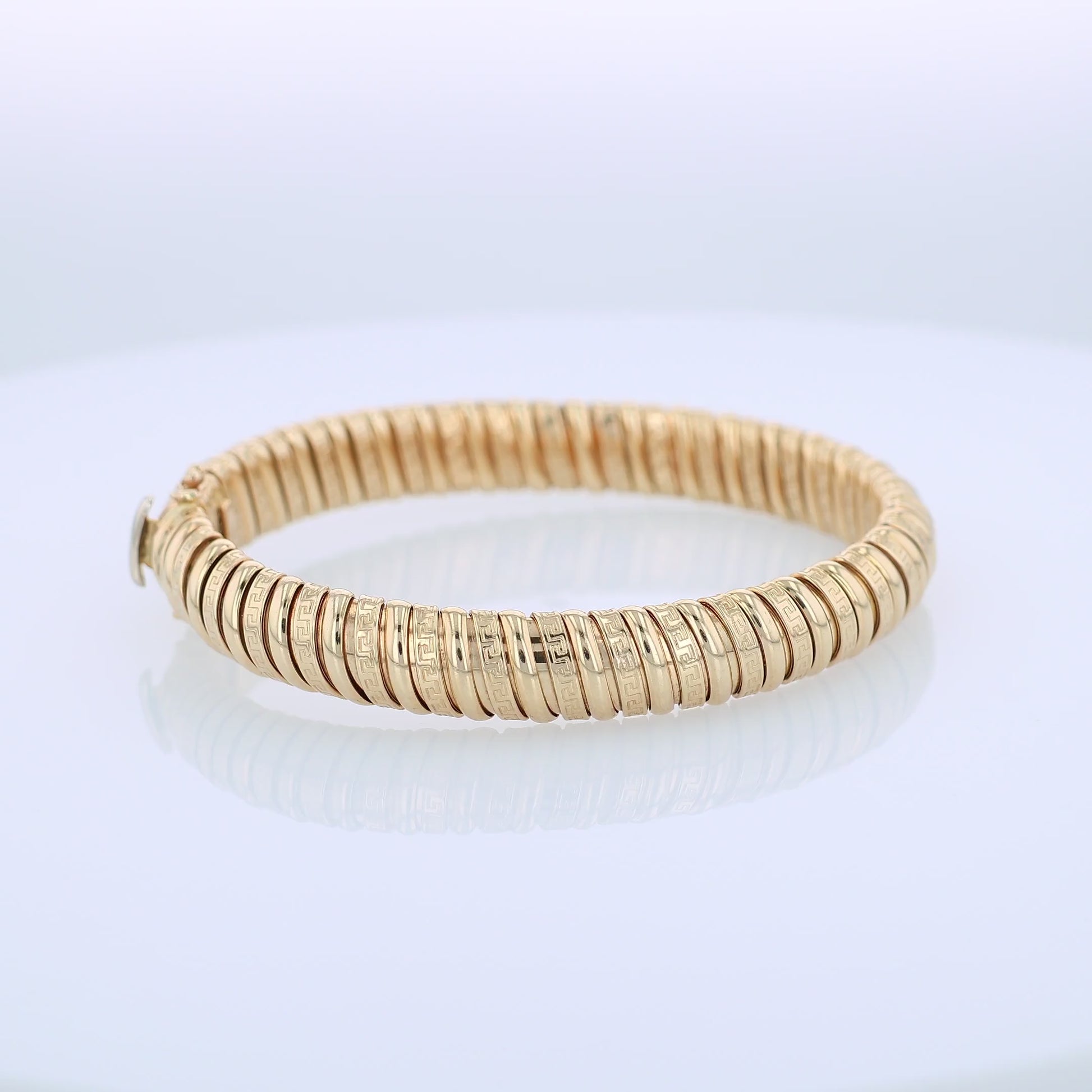 360 degree video of a yellow gold alternating polished and greek key design soft tubogas bangle bracelet on a white background