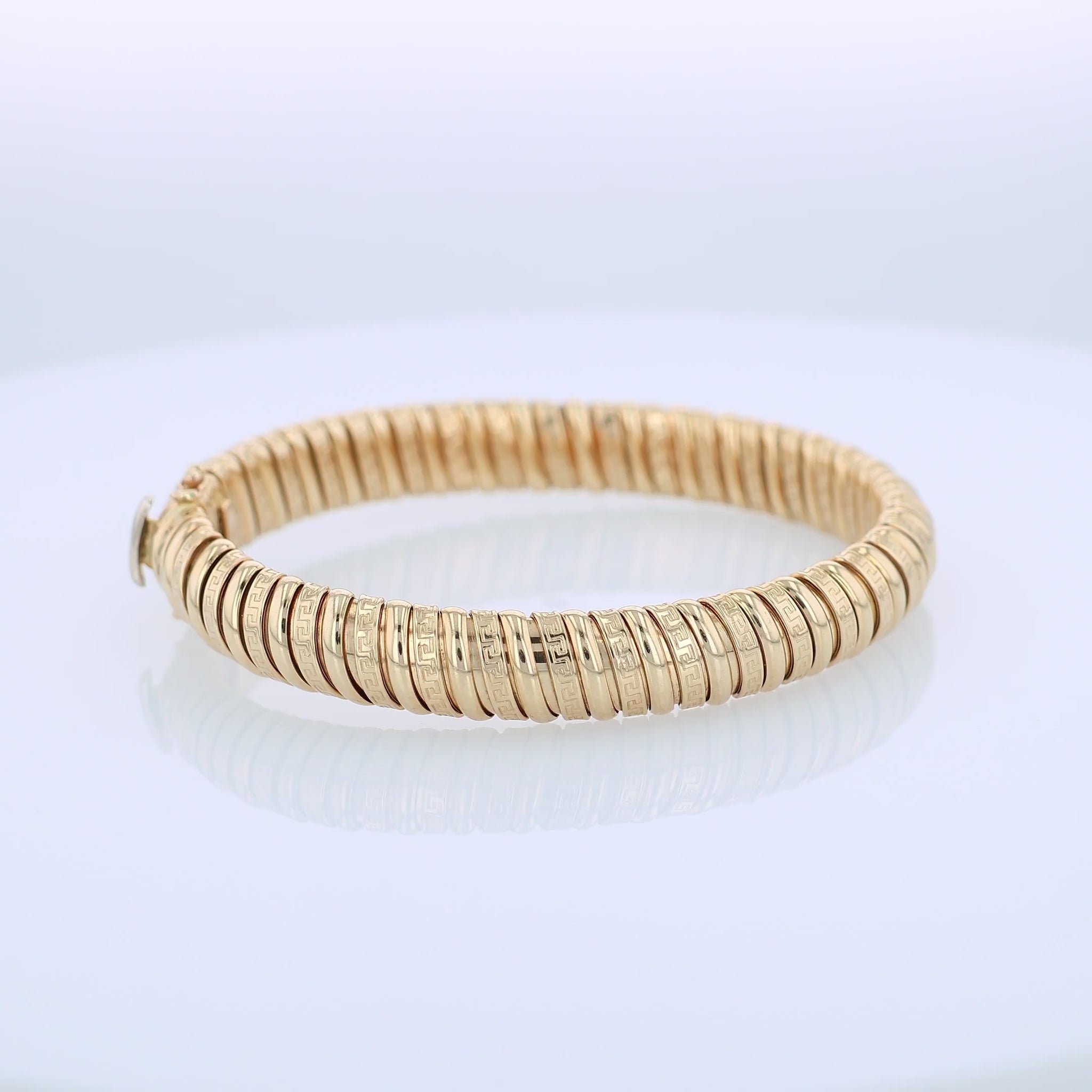 360 degree video of a yellow gold alternating polished and greek key design soft tubogas bangle bracelet on a white background