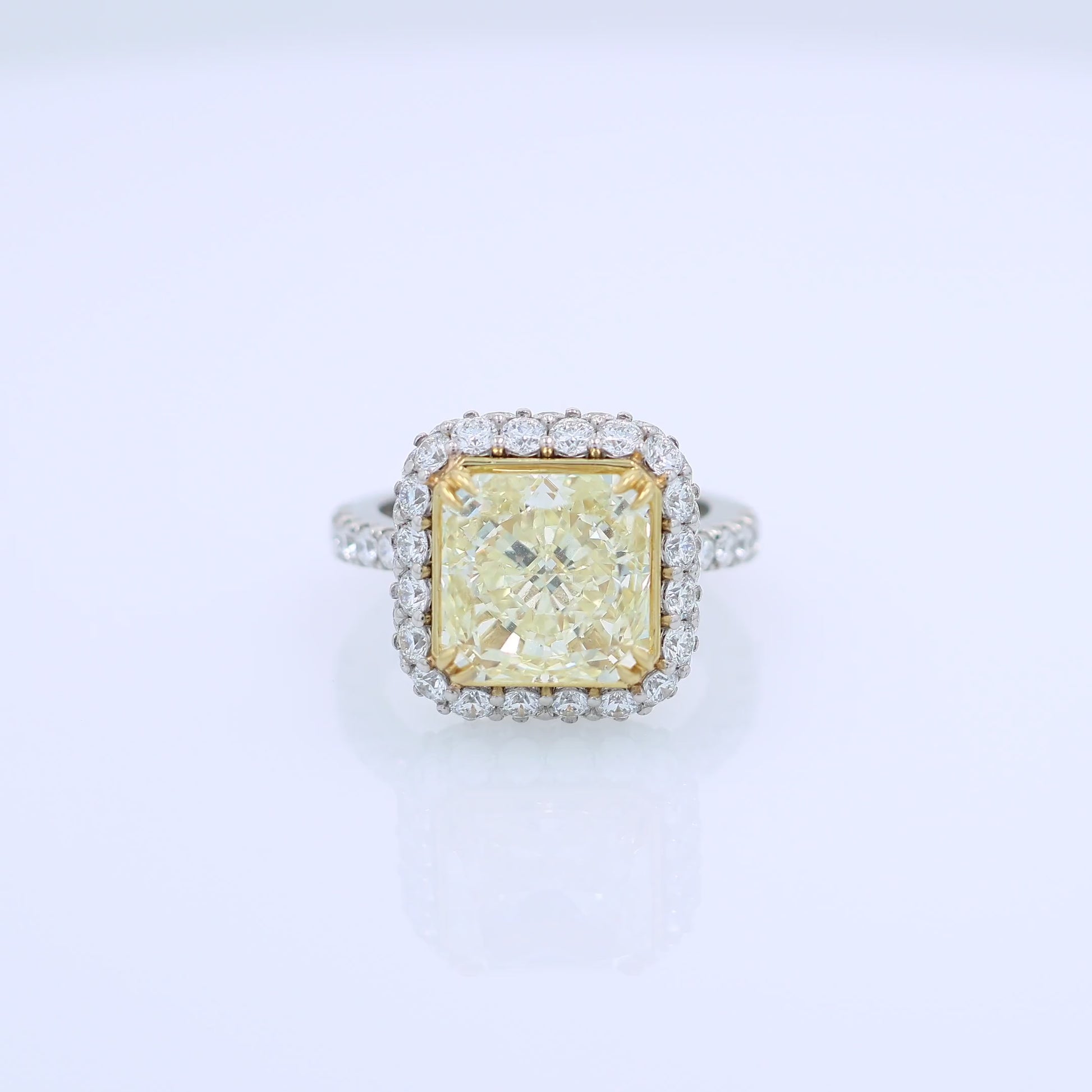 Platinum diamond halo ring with a yellow diamond center on a white background
