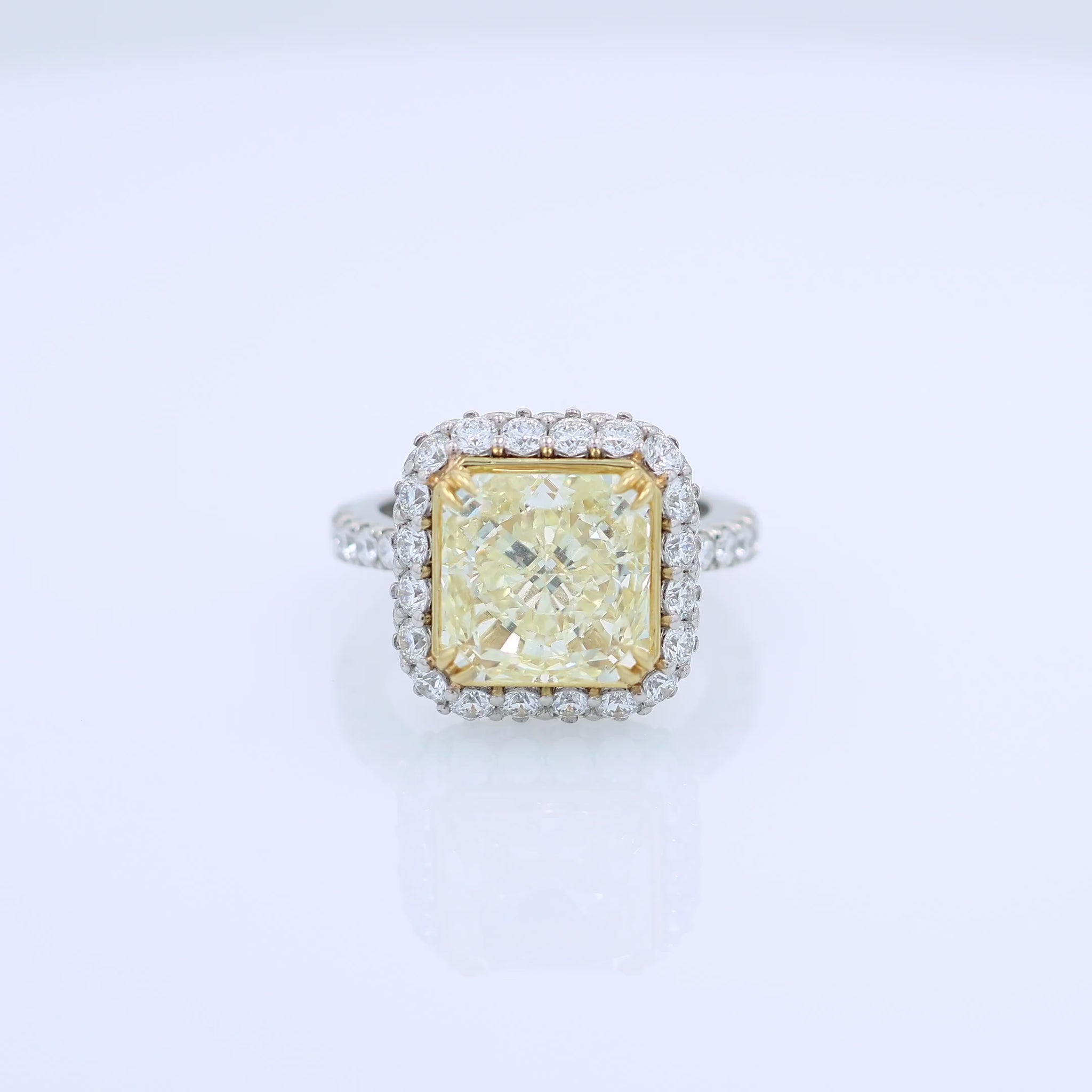 Platinum diamond halo ring with a yellow diamond center on a white background