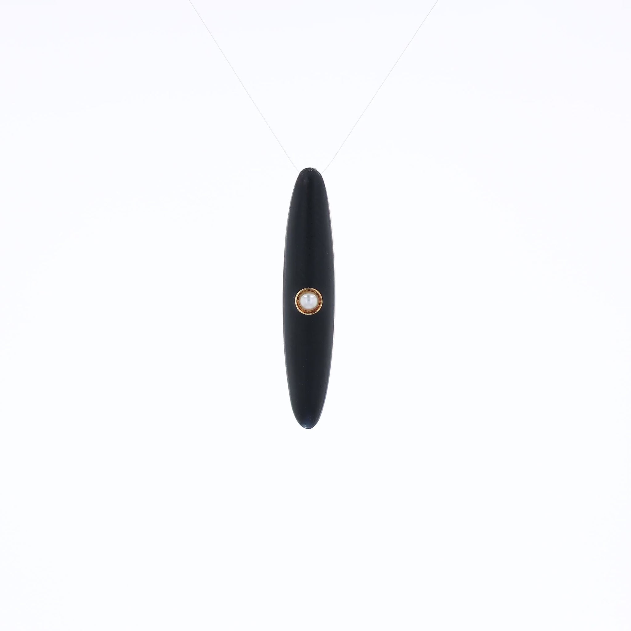 Yellow gold and black enamel pin with a pearl center on a white background