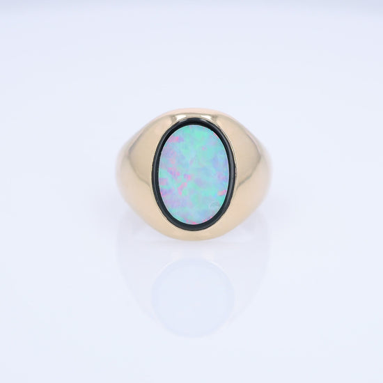 Yellow Gold oval opal doublet signet style ring on a white background