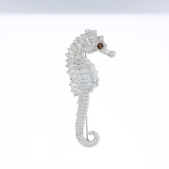 Sterling silver seahorse pin with a round tiger's eye in the eye on a white background