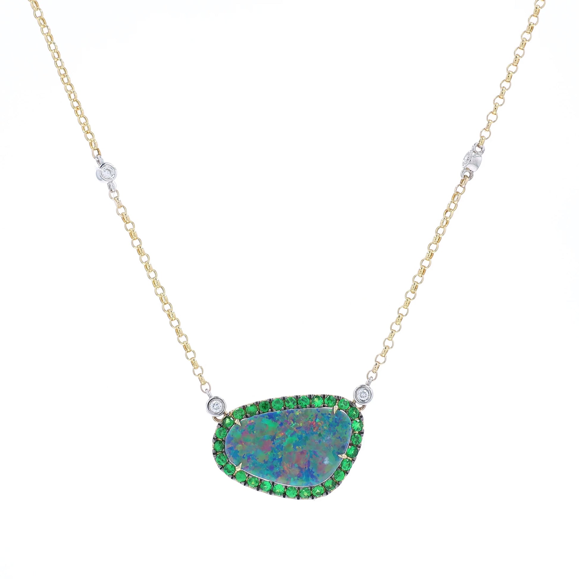 Yellow and white gold freeform opal, green tsavorite, and diamond halo pendant necklace on a white background