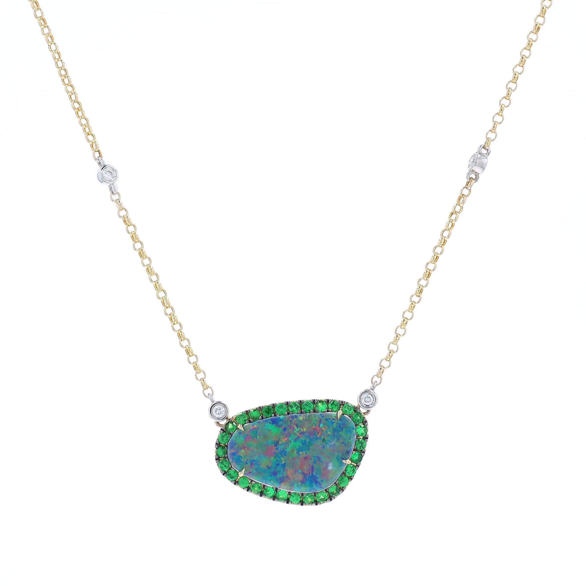 Yellow and white gold freeform opal, green tsavorite, and diamond halo pendant necklace on a white background