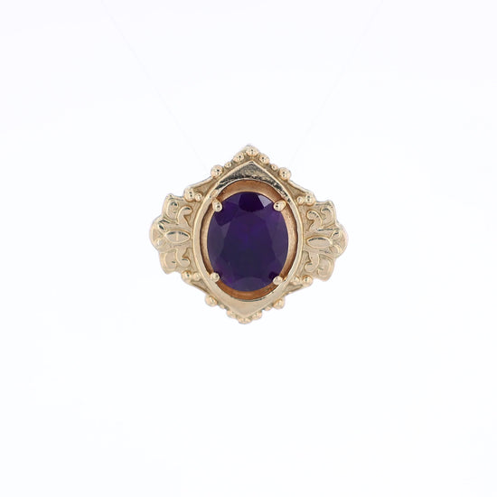 Yellow gold oval amethyst slide pendant with an ornate shield shaped frame on a white background