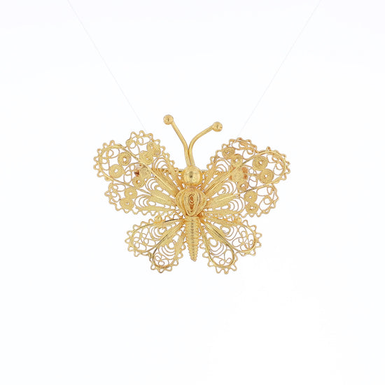 Yellow gold filigree design butterfly pin on a white background