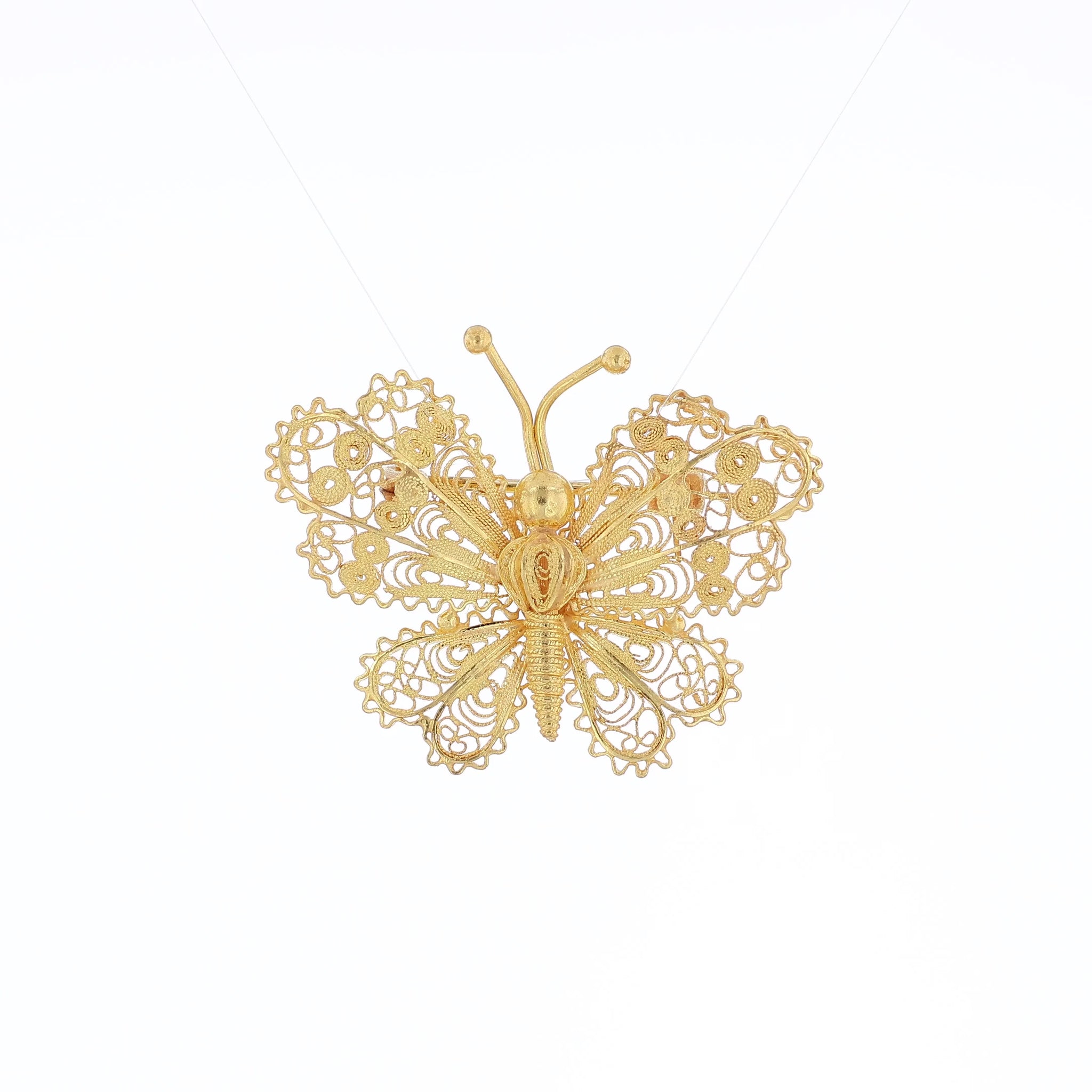 Yellow gold filigree design butterfly pin on a white background