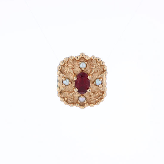 Yellow gold slide pendant with an oval garnet center and surrounding pearls on a white background